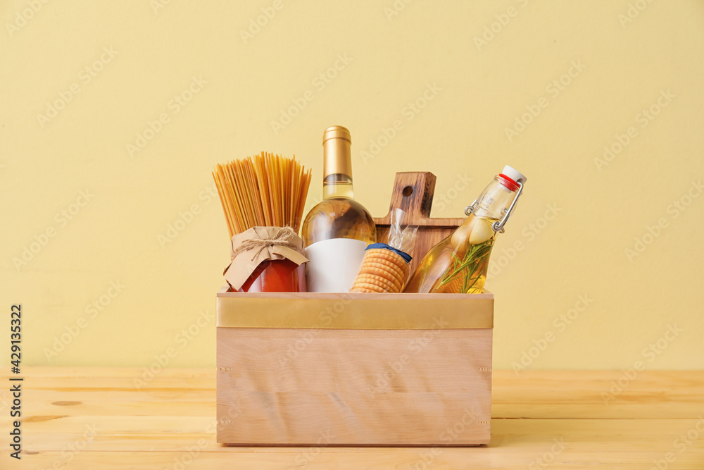Gift basket with products on color background