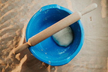 Wall Mural - Top view of dough in a blue bowl with a rolling pin