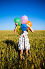 Wall Mural - Girl with balloons at wheat field