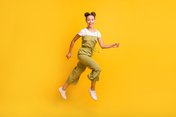 Wall Mural - Full length body size view of charming cheerful girl jumping running having fun isolated over bright yellow color background