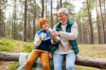 Canvas Print - picking season, leisure and people concept - grandmother and grandson having picnic and drinking tea in autumn forest