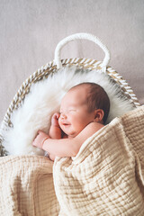 sleeping newborn baby in basket wrapped in blanket in white fur background. portrait of little child