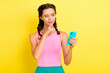 © deagreez - Photo of cute thoughtful young woman pigtails wear tank top finger chin looking modern device isolated yellow color background