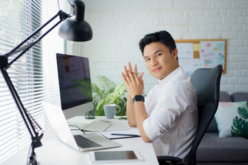 Poster - Asian businessman handsome happy and smiling with a laptop while sitting in the workspace.