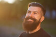 © endrews21 - Laughing brutal stylish adult man with a long black beard and mustache in a dark shirt against the sunset sky