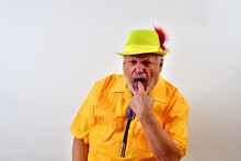 Senior Male In A Yellow Outfit Doing A Gagging Pose In Front Of A White Wall
