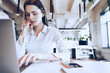 © fotofabrika - Portrait of a young smart businesswoman sitting at her working table in office