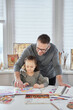 © boytsov - Happy family coronavirus covid-19 activity at home. Beautiful caring father teaching to draw cute girl sitting at the table, dad enjoy helping child daughter doing homework. High quality image