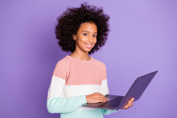 Portrait of optimistic curly hairdo girl type laptop wear white sweater isolated on violet background