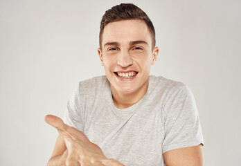 A cheerful man in a white T-shirt gestures with his hands emotions close-up