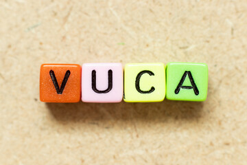 Poster - Color alphabet letter block in word VUCA (abbreviation of Volatility, uncertainty, complexity and ambiguity) on wood background