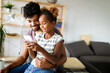 © NDABCREATIVITY - Happy father and daughter having fun with smartphone, smiling at funny video, playing mobile game
