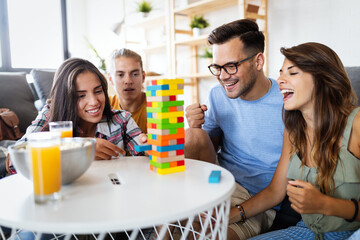 Group of young happy friends having fun playing wood board game