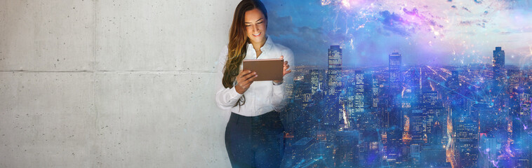 Young business woman with tablet standing against concrete wall in office.