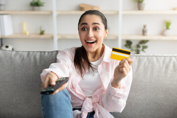 Wall Mural - Excited woman holding remote control and debit credit card