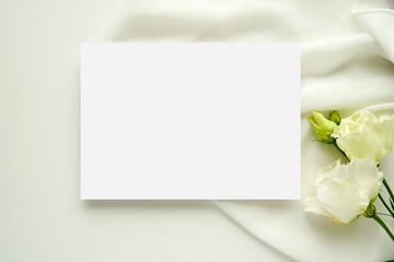 Wedding stationery mockup, white blank horizontal card for design presentation, flat lay composition with white flowers and bride dress.