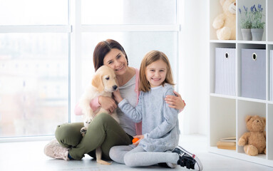 Poster - Smiling mother and daughter embracing cute dog