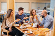 © Andrii - A group of young cheerful friends is sitting in a cafe talking and eating pizza. Lunch at the pizzeria.