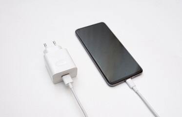 Charging a smartphone via a USB cable on a white background, top and side view. Silhouette of black smartphone with usb charging cable and power supply on white empty space.copy space. selective focus