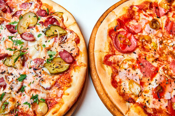 Pizza with salami, bell pepper, tomatoes and cheese, pickles, bacon and sausages on a light background. Close-up, selective focus