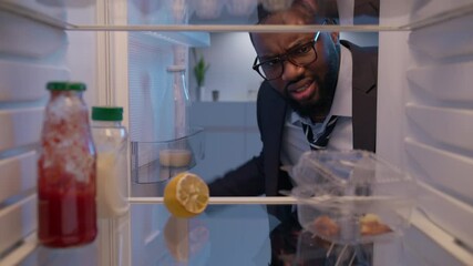 Wall Mural - hungry man opening fridge looking inside searching for food and disappointed. view from inside the w