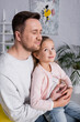 © LIGHTFIELD STUDIOS - Smiling daughter sitting on laps of father at home.