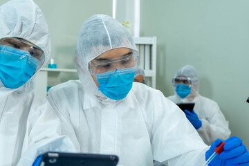 Asian medical scientists in PPE protective suit research for virus pandemic vaccine in clinical laboratory