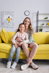 Wall Mural - Smiling mother looking at camera while hugging child.