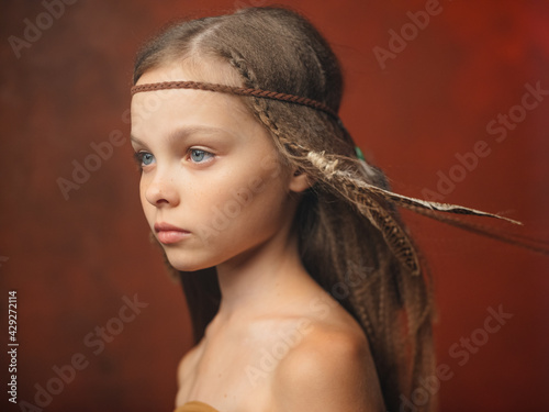 Plakat The girl on a red background with an ornament on the head of a feather aborigines savage