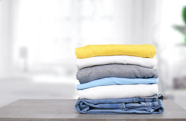 Wall Mural - Stack of cotton colorful clothes on table indoors.Stacked apparel.Folded clean clothing.