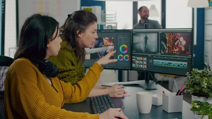 Poster - Art video director explaning to woman videographer the steps for prosessing film montage, pointing on pc, writting on sticky notes. Video editor working in post production software in creative agency