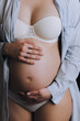 © shchus - A beautiful pregnant girl holds a belly tenderly with her hands in lingerie. Photo of a sixth month pregnancy.