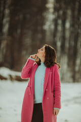 Poster - Vertical shot of a Bosnian woman in a pink coat posing in the winter