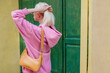 Street style, fashion details: yellow faux leather shoulder bag in trendy outfit. Woman wearing pink hoodie. Copy, empty space for text