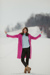 Sticker - Vertical shot of a stylish Bosnian woman posing near the snowy forest in the winter