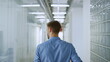© stockbusters - Unknown man walking through glass wall space. Businessman looking around office