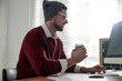 © New Africa - Freelancer with cup of coffee working on computer at table indoors