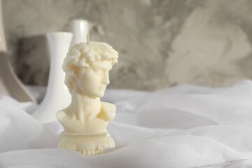 Wall Mural - Beautiful David bust candle on white fabric. Space for text