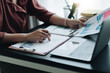© Natee Meepian - Close up view of bookkeeper or financial inspector hands making report, calculating or checking balance. Home finances, investment, economy, saving money or insurance concept.