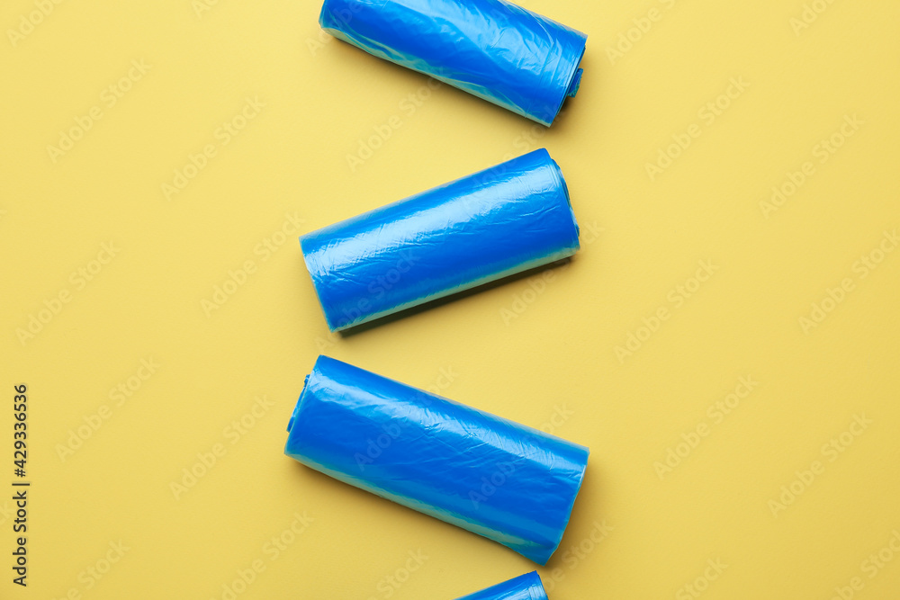 Rolls of garbage bags on color background