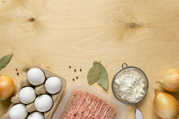 Wall Mural - Ingredients for cooking dumplings. Minced meat, eggs, flour and spices on wooden background, top view