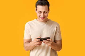 Wall Mural - handsome young man with mobile phone on color background