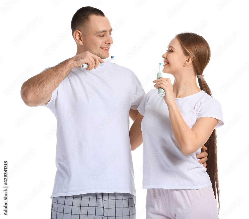 Young couple brushing teeth on white background
