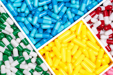 Poster - Top view colorful antibiotic capsule pills in plastic box. Antibiotic drug resistance concept. Drug of choice. Drug selection for treatment infectious disease. Pharmaceutical industry. Pharmacology.