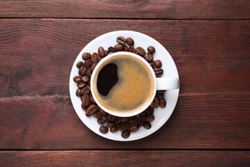 Cup of hot aromatic coffee and roasted beans on wooden table, top view