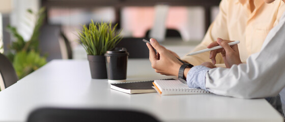 Side view of two office worker hands using digital tablet while discussing on their work