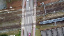 Aerial Top Down View Of Level Crossing High Speed Train Passing Over The Intersection Where A Railway Line Crosses A Road Showing The Vehicles Waiting On Both Sides And Drive Through After Gates Open