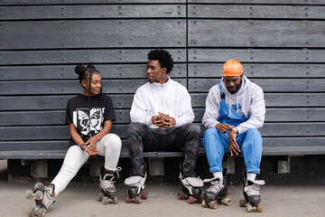 Group of friends with roller skates sitting on bench 