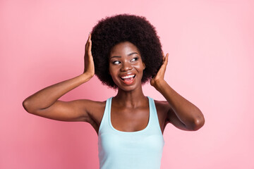 Sticker - Portrait of optimistic brunette curly lady hand hair look empty space wear blue top isolated on pink color background