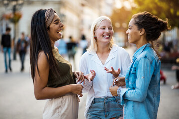 Three women standing on street and talking.